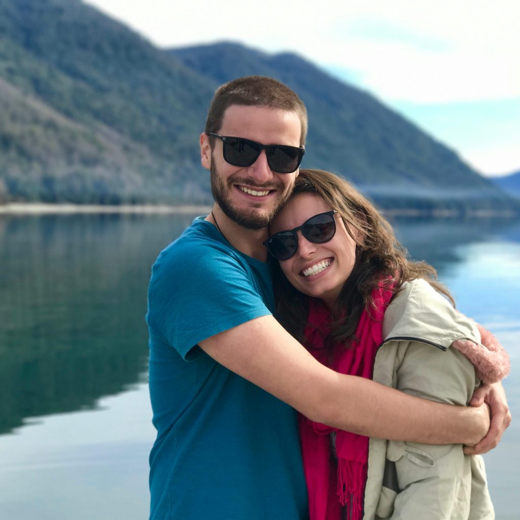 A joyful couple shares a warm embrace by a serene mountain lake, symbolizing love and togetherness.